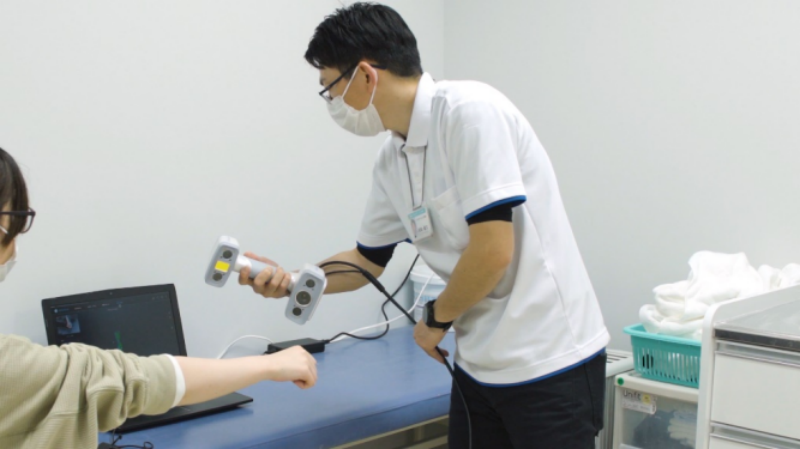 Kenta Matsuda en train de numériser le bras d'un patient en 3D.
